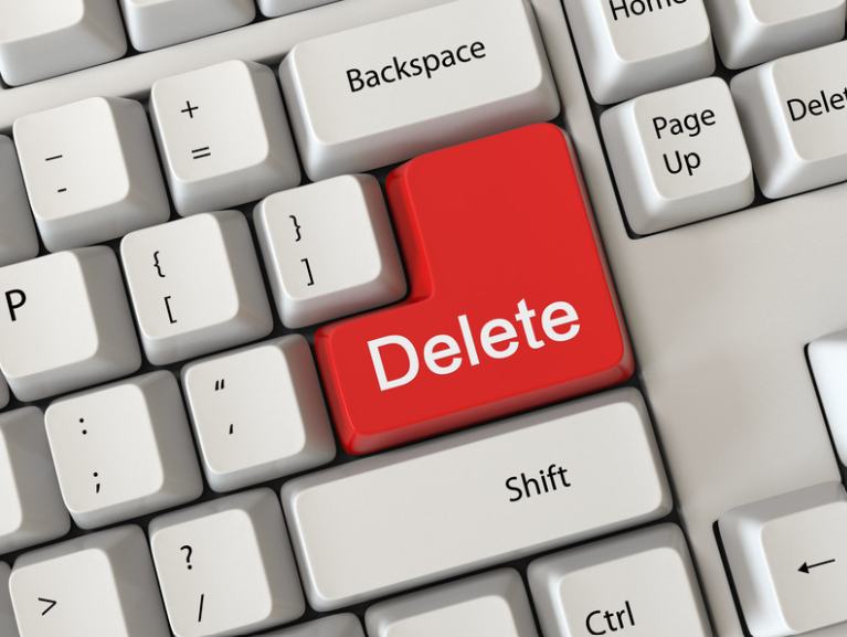 Close-up of a white computer keyboard with black lettering and a bright red Delete key centered among gray and white keys.