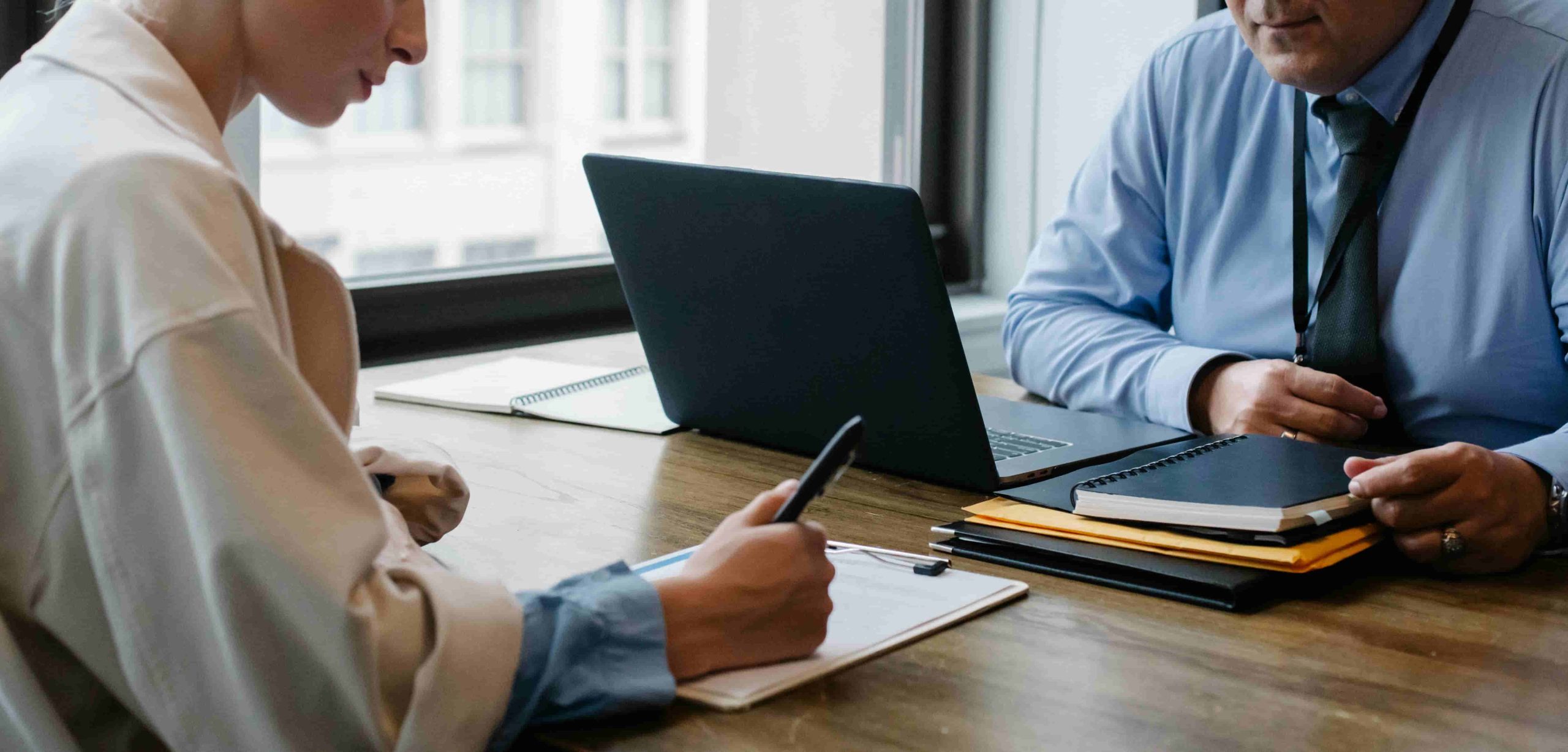 A man and woman engaged in a laptop discussion at a table, related to Debt Collection.