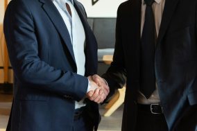 Two business men shaking hands in a modern office, symbolizing a successful partnership or agreement.